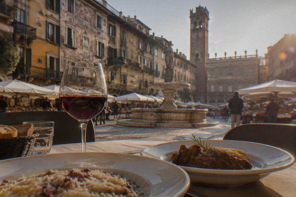 A table of Veronese dishes with risotto, stewed meat and a glass of red wine