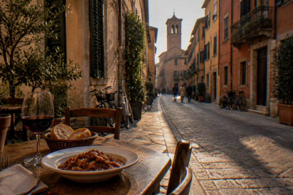 A rustic restaurant table with a plate of stew, a glass of red wine and bread