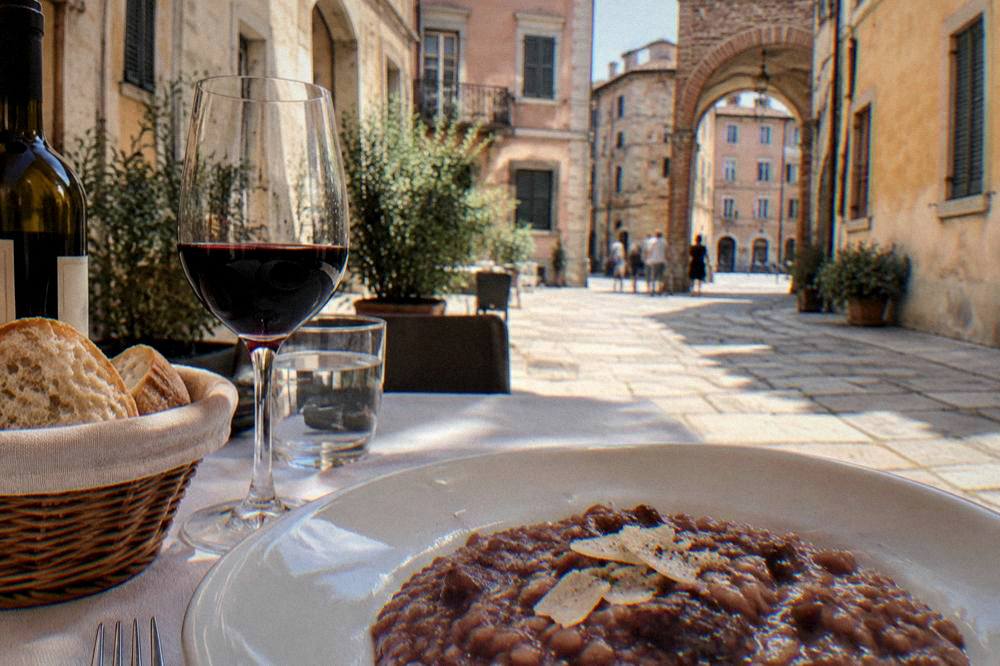 A table set with risotto all'Amarone, bread and a bottle of red wine in a Verona dining room