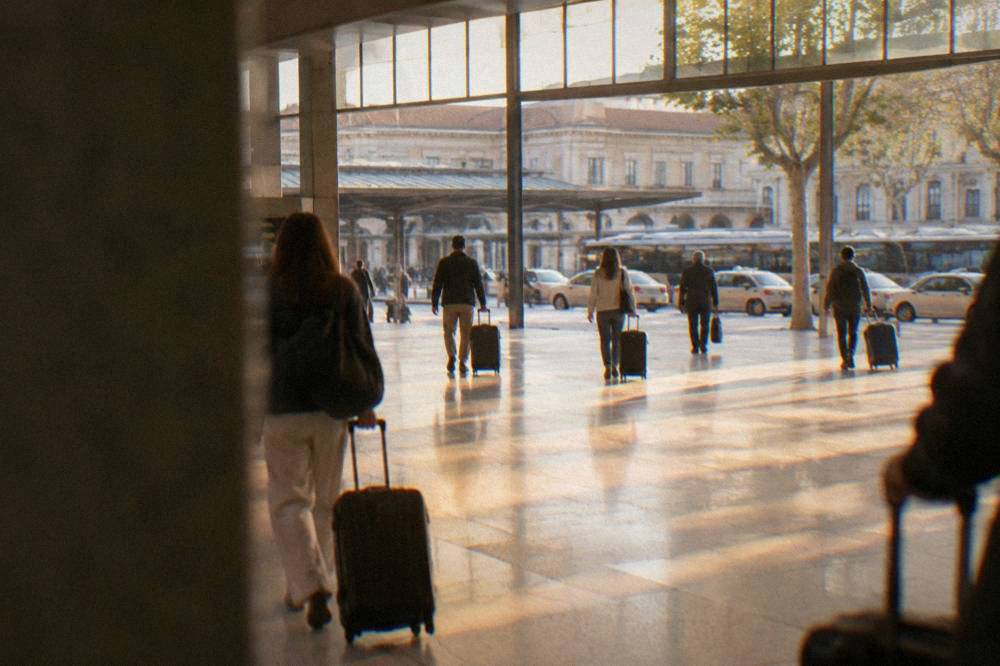 Travellers with suitcases walking through a bright modern railway station concourse