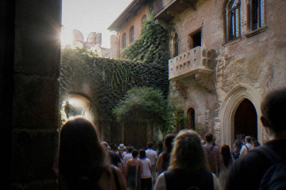 Crowded courtyard of Juliet's House in Verona with the stone balcony above