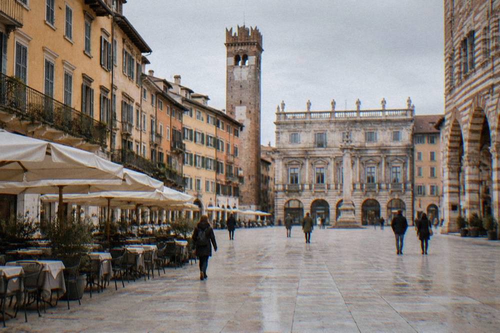 A flat wide marble square in Verona with cafe tables and historic facades