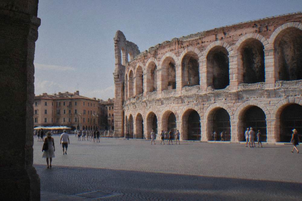 The rose-pink Roman amphitheatre of Verona seen from the flat open square beside it