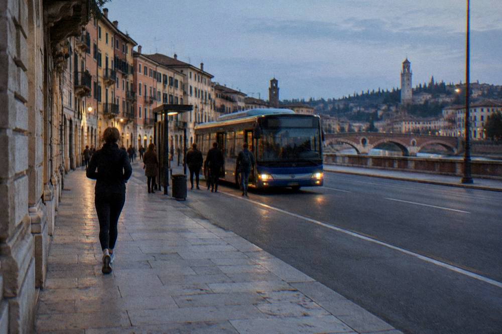 A city bus stopped at a stop in Verona with a wide flat street in front of it