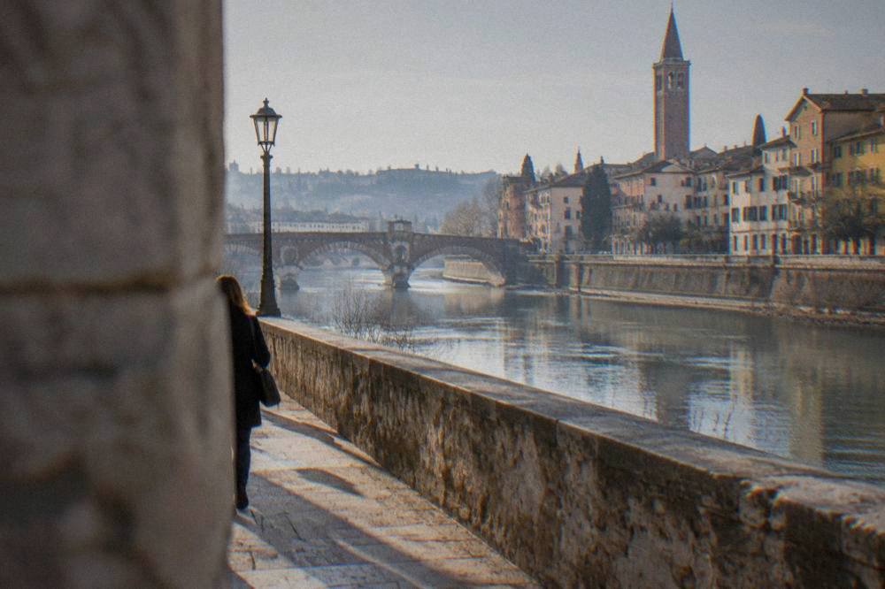 A calm stretch of the Adige river in Verona with old stone bridges and riverside walls