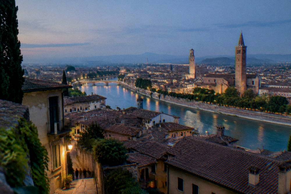 An evening view over Verona rooftops with the Adige river curving through the city
