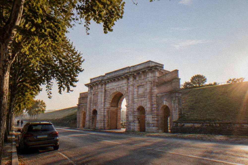 A rental car parked on a tree-lined road outside Verona's city walls