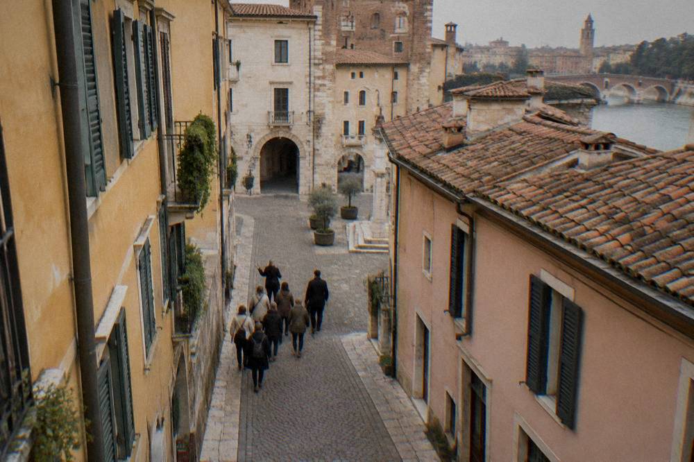 A small group of visitors following a guide along a narrow cobbled street in Verona