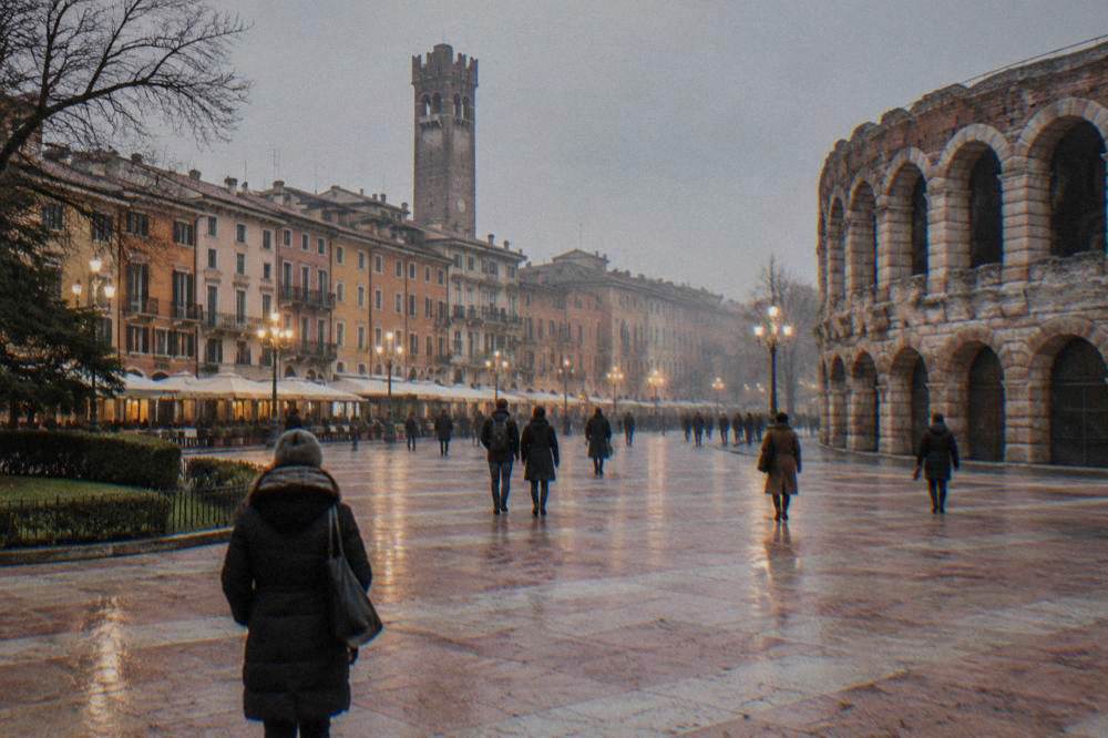 A tall medieval stone tower rising above narrow rooftops and a lit public square at dusk in winter