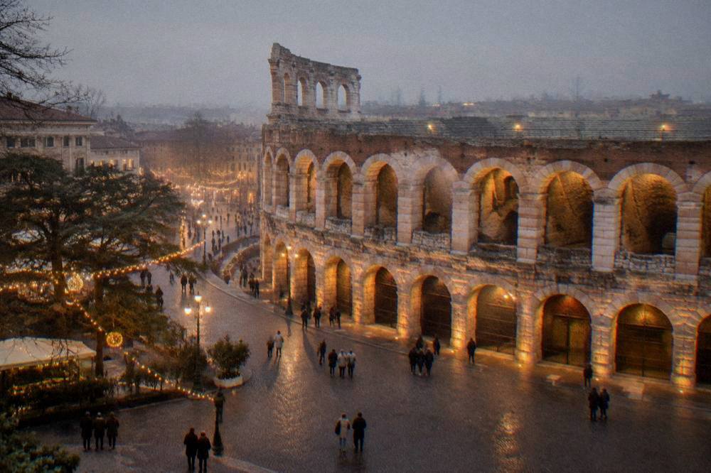 A Roman amphitheatre lit by warm floodlights at night with strings of festive lights glowing in the square in front of it