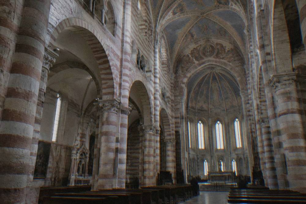 Interior of a large Verona church with striped stone columns and painted vaults