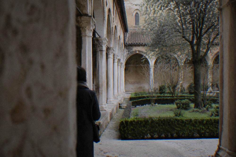 A cathedral cloister with stone columns and a quiet garden in Verona
