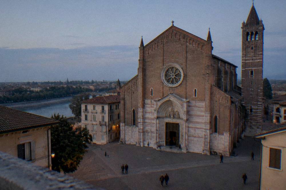 The Romanesque facade and rose window of a basilica above an open piazza