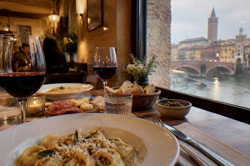A table set with wine glasses and local dishes in a warmly lit Verona dining room