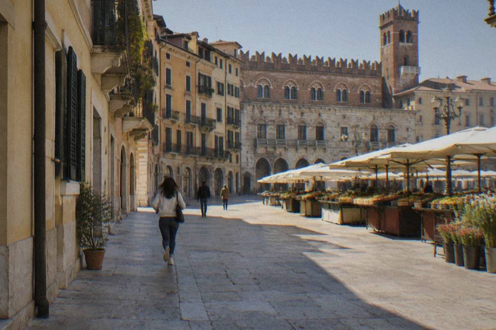 A quiet morning in a Verona piazza with market stalls and historic buildings