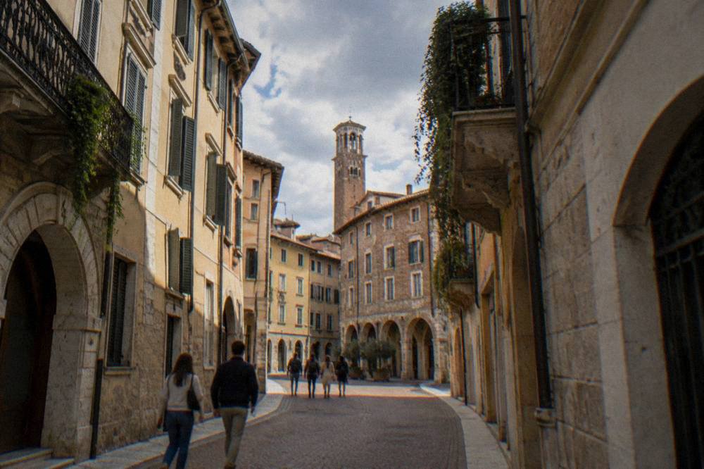 Visitors walking along a narrow brick street in central Verona