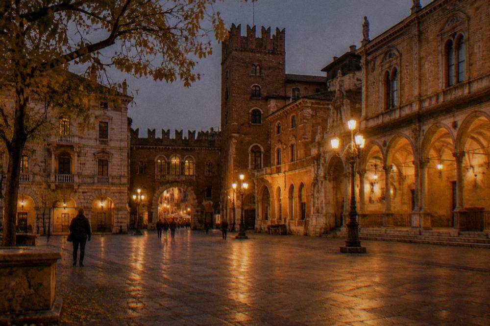 Lamplit Piazza dei Signori in Verona on a dark autumn evening with few people around