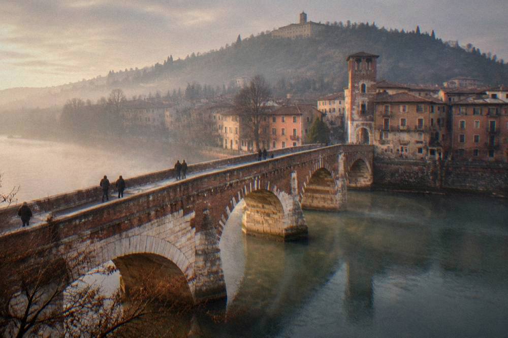 Fog settling over the Adige river and Ponte Pietra at sunrise in late autumn