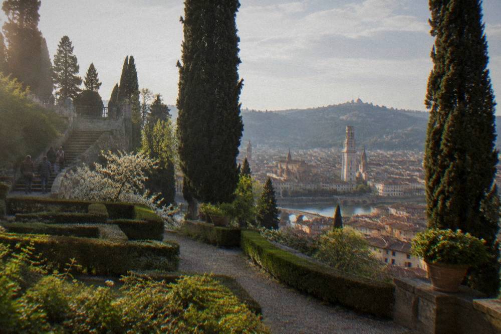 A spring view over Verona's terracotta rooftops toward the hills beyond the Adige