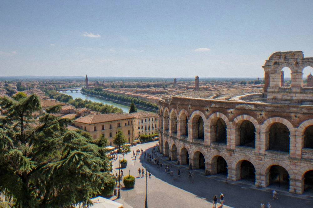 A wide view over Verona's rooftops and the Adige river bend in summer morning light