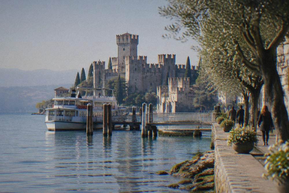 The lakeside promenade at Sirmione on Lake Garda with a ferry at the pier and the Scaliger castle tower behind