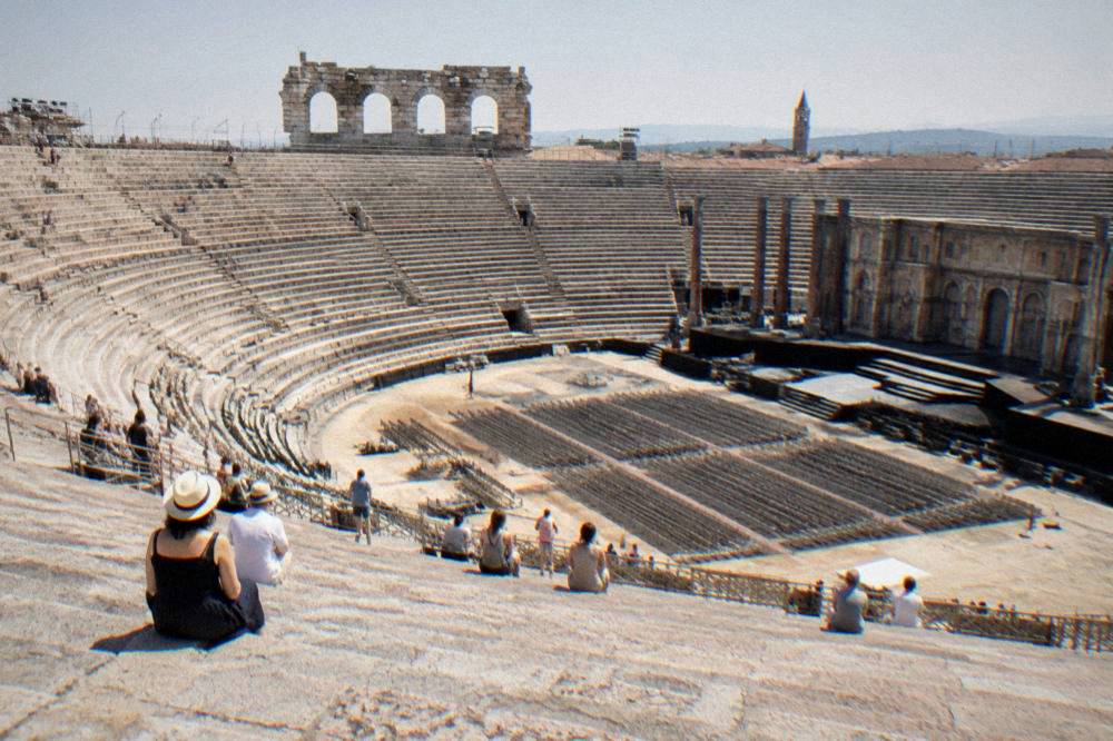 The interior of the Verona Arena amphitheatre in daylight with its stone seating tiers and stage set visible