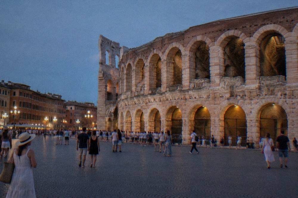 Verona's Arena amphitheatre lit at dusk with crowds in Piazza Bra