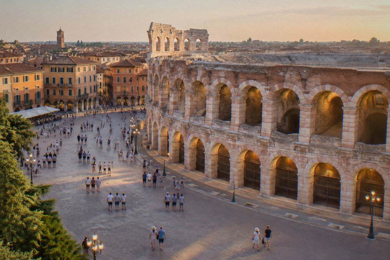 Piazza Bra at dusk with the Arena amphitheatre lit by warm lamplight and people strolling