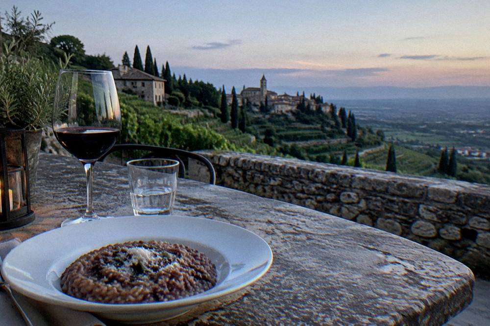 A plate of risotto with red Amarone wine and a glass of local wine beside it