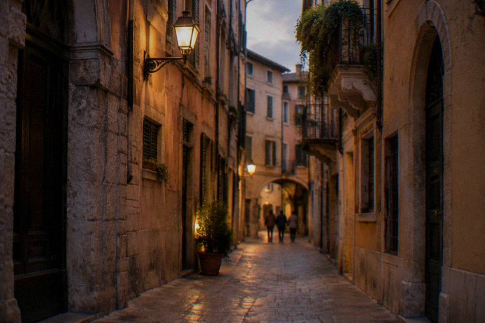 A quiet lamplit alley in Verona's historic centre late in the evening