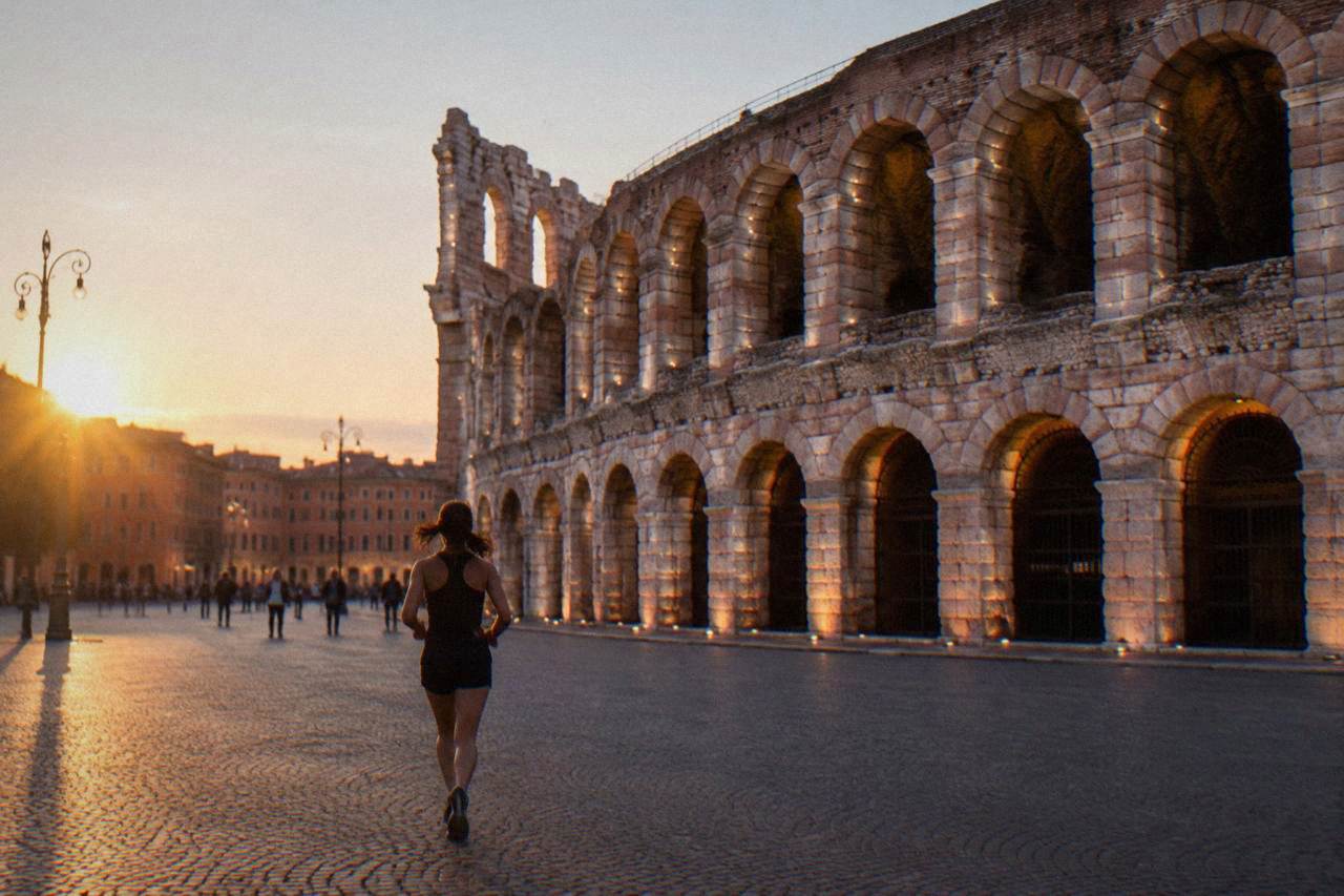 The floodlit Roman Arena of Verona at dusk, seen from the edge of Piazza Bra