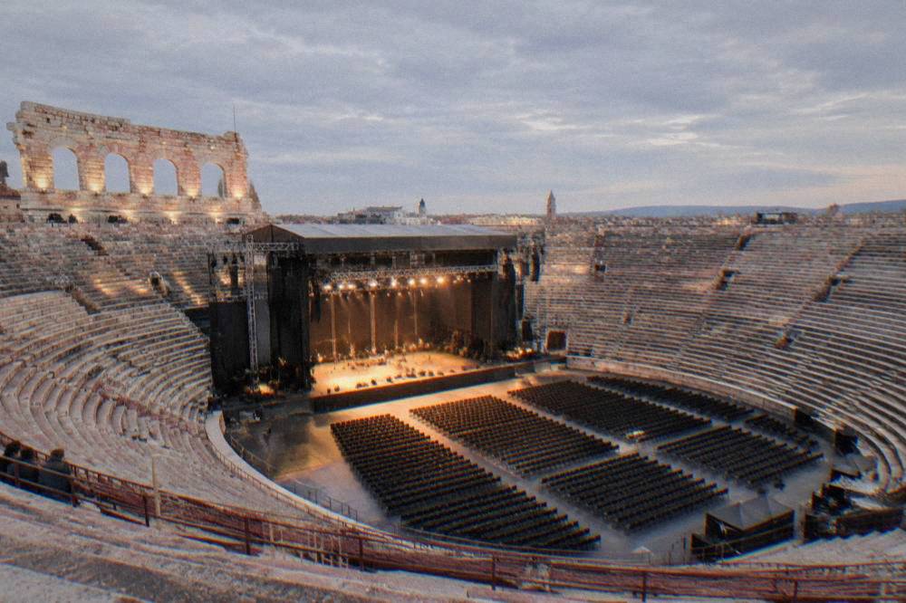 A wide view inside the Arena of Verona showing the stage structure and tiered seating during an opera performance
