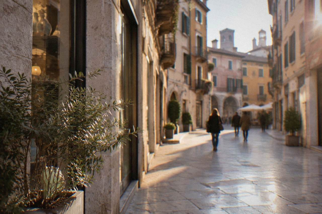 A marble-paved pedestrian street in Verona lined with shopfronts under pastel buildings