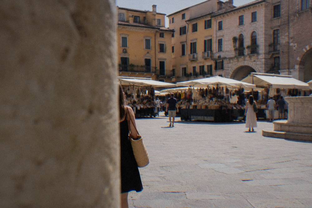 A broad stone-paved square in Verona with market stalls and historic buildings