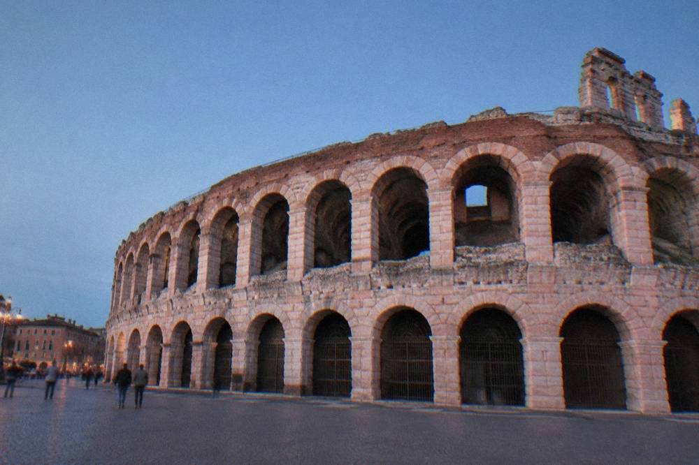 The pink marble facade of the Verona Arena seen from Piazza Bra under a clear sky