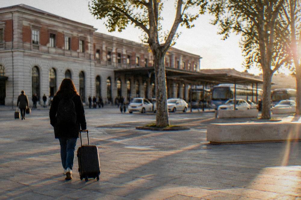 A traveller pulling a suitcase across the forecourt outside Verona Porta Nuova station