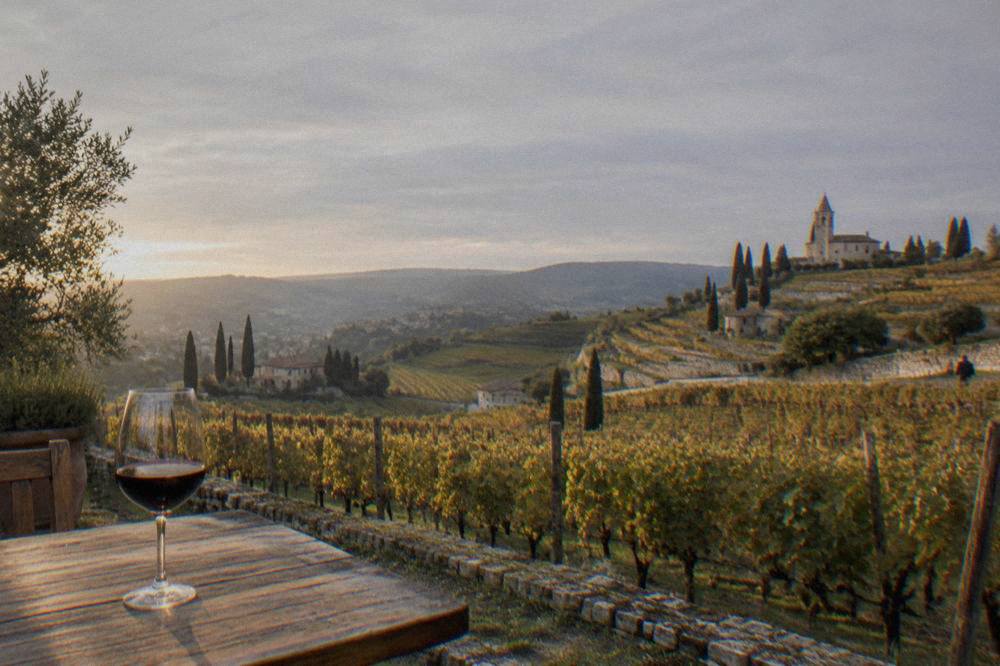 A glass of red wine on a wooden table beside a vineyard at golden hour