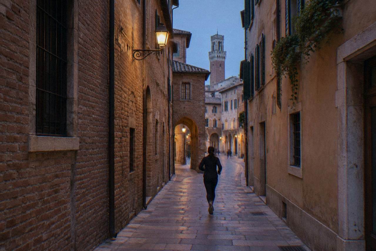 A narrow street of old brick buildings in central Verona with a restricted traffic sign and a CCTV camera mounted on a wall