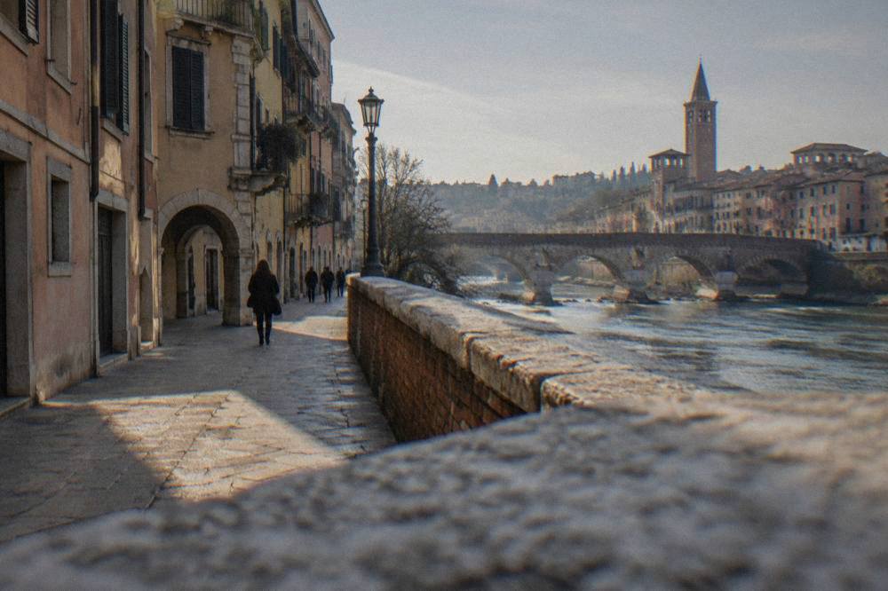 A blue ZTL restricted traffic sign on a stone wall beside an old city gate in Verona