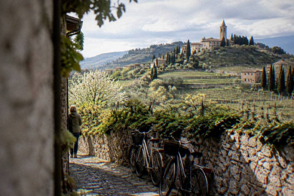 Bicycles parked on a cobbled lane beside an old stone wall with vines