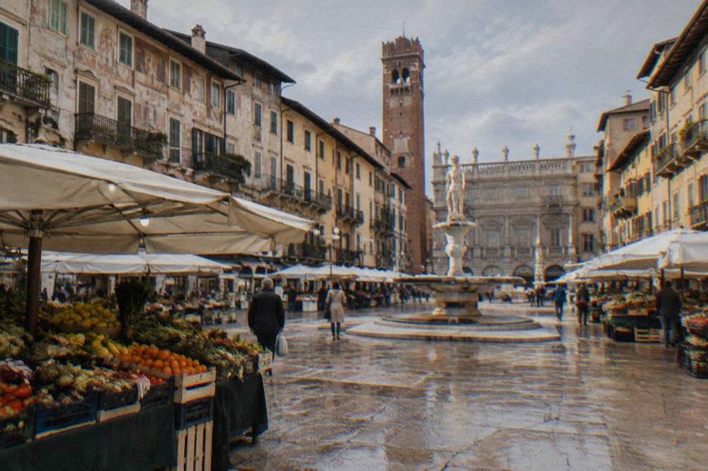 A market stall with fruit and vegetables under awnings in an old square