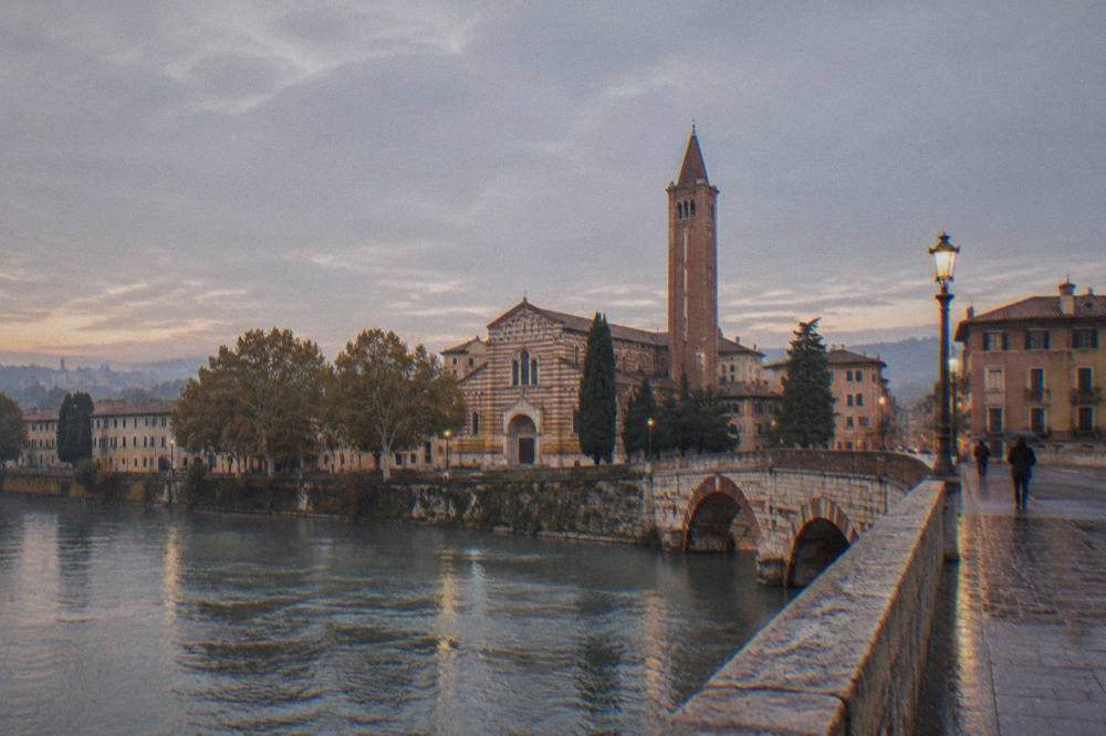 A stone bridge crossing the Adige river toward Verona's old centre at dusk