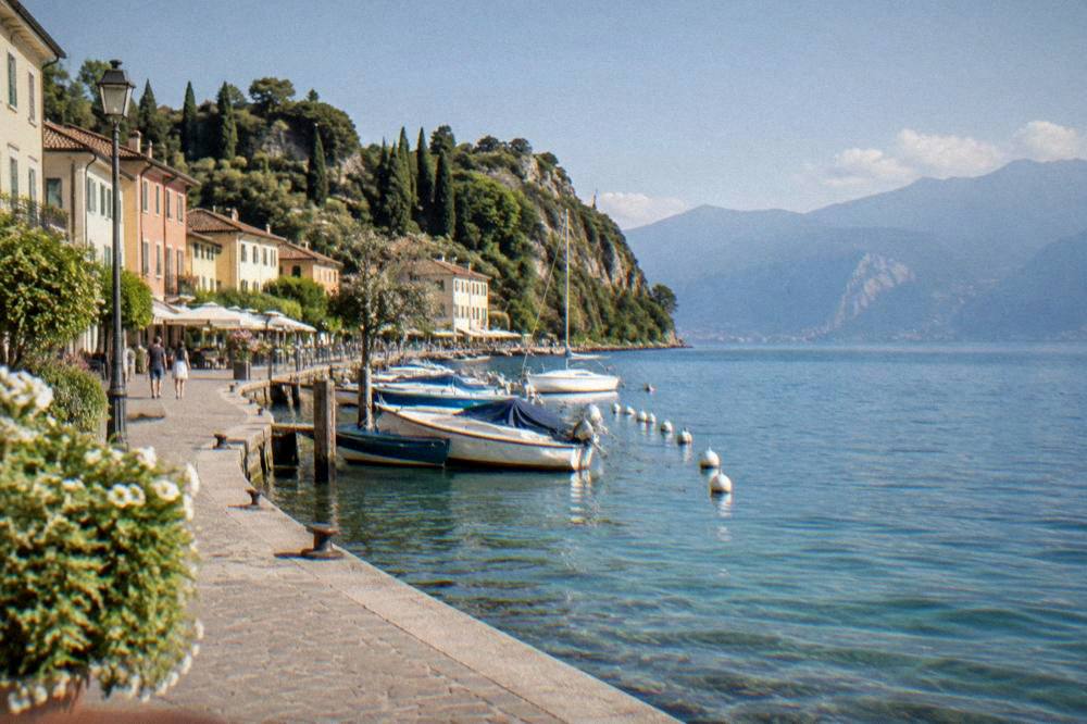 A lakeside promenade with boats and hills at Lake Garda
