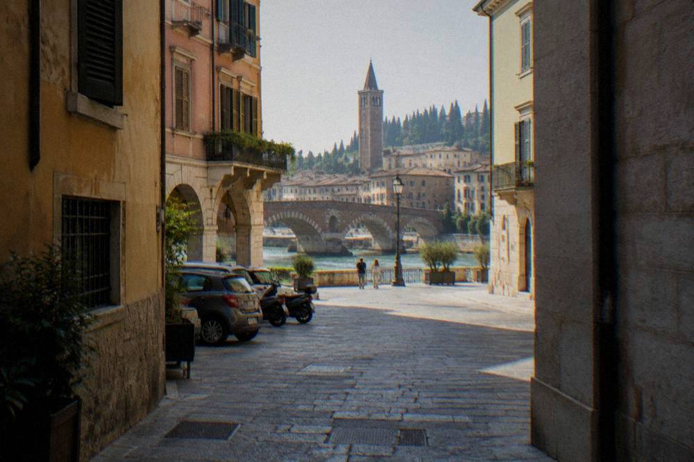 Cars and scooters parked outside old city walls in Verona