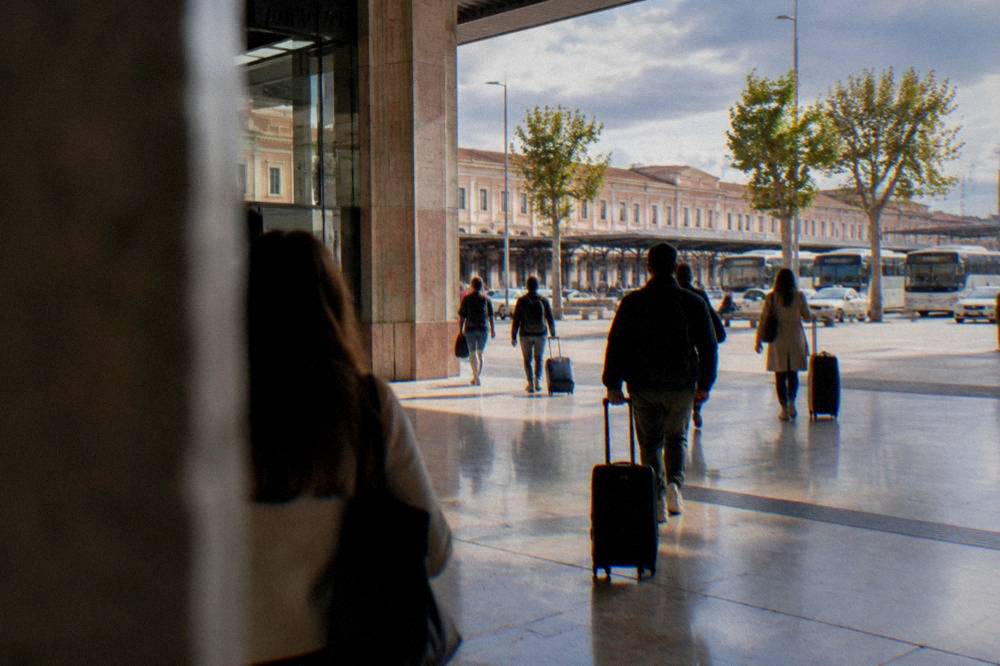 Travellers with suitcases walking through Verona Porta Nuova station concourse