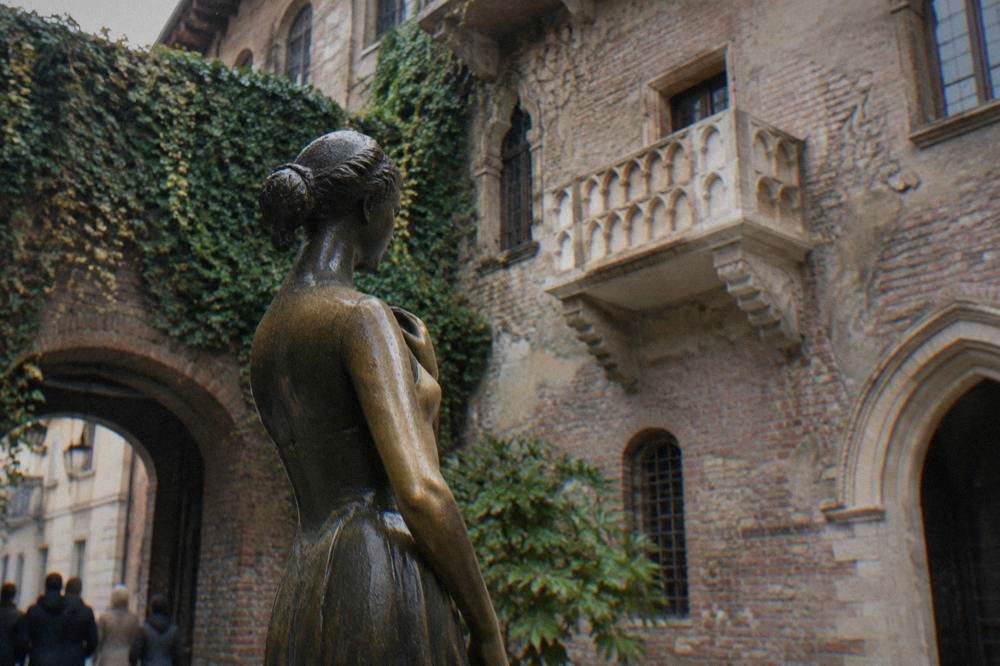 Juliet's bronze statue standing in the courtyard of Casa di Giulietta