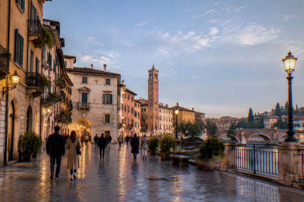 Lit evening streets in central Verona with people walking after a performance