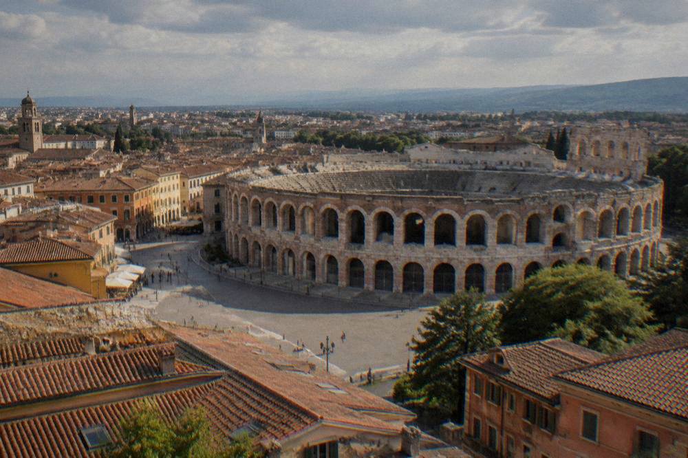 Daytime view over Verona rooftops with the Arena and distant hills in the background