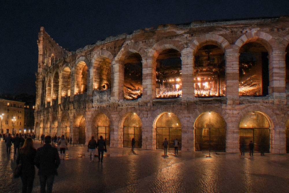 The Verona Arena lit at night with the stage glowing inside the stone bowl