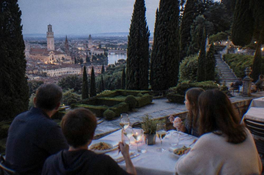 A family sharing a table of pasta, wine glasses and gelato at an outdoor restaurant